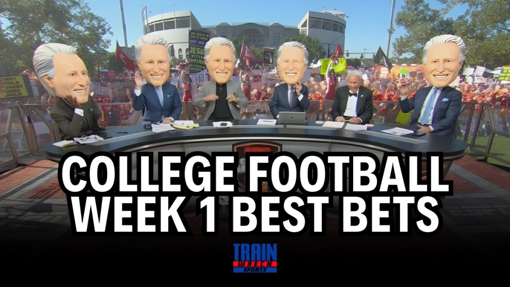 ESPN College GameDay set with all hosts wearing oversized Lee Corso mascot heads, surrounded by a lively college football crowd holding signs, with bold text overlay that reads 'College Football Week 1 Best Bets' and a Trainwreck Sports logo at the bottom.